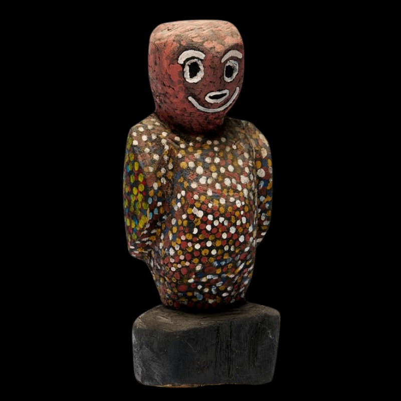 Carved wooden Night Owl figure by Angelina Pwerle, with a red head, white painted facial features and a body covered in multicoloured dots.