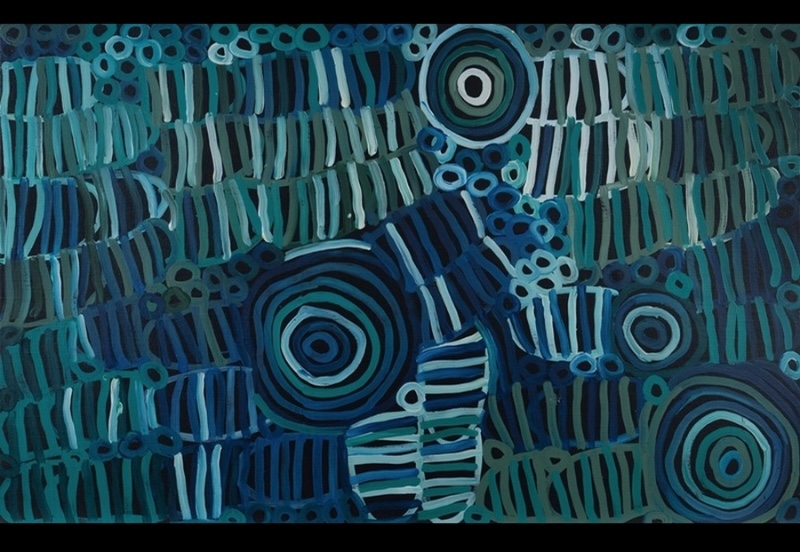 Minnie Pwerle painting in shades of blue and turquoise, with large concentric circles surrounded by overlapping striped forms and clusters of small rings against a dark ground.