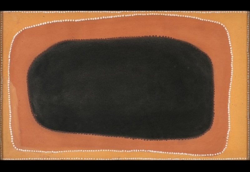 Rover Thomas painting with a large rounded black rectangular form dominating the centre of an orange and reddish-brown ochre field. A single curving row of small white dots surrounds the black shape, with further white dotted lines framing the outer edges of the canvas.