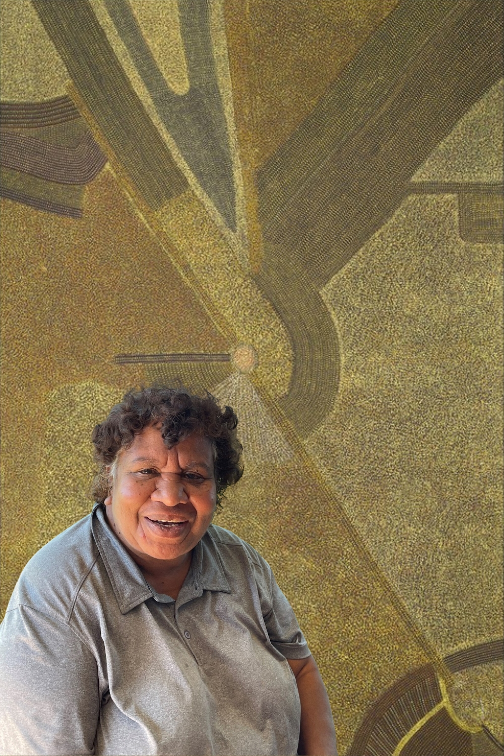 Abie Loy Kemarre seated in front of one of her large paintings of Utopia Country