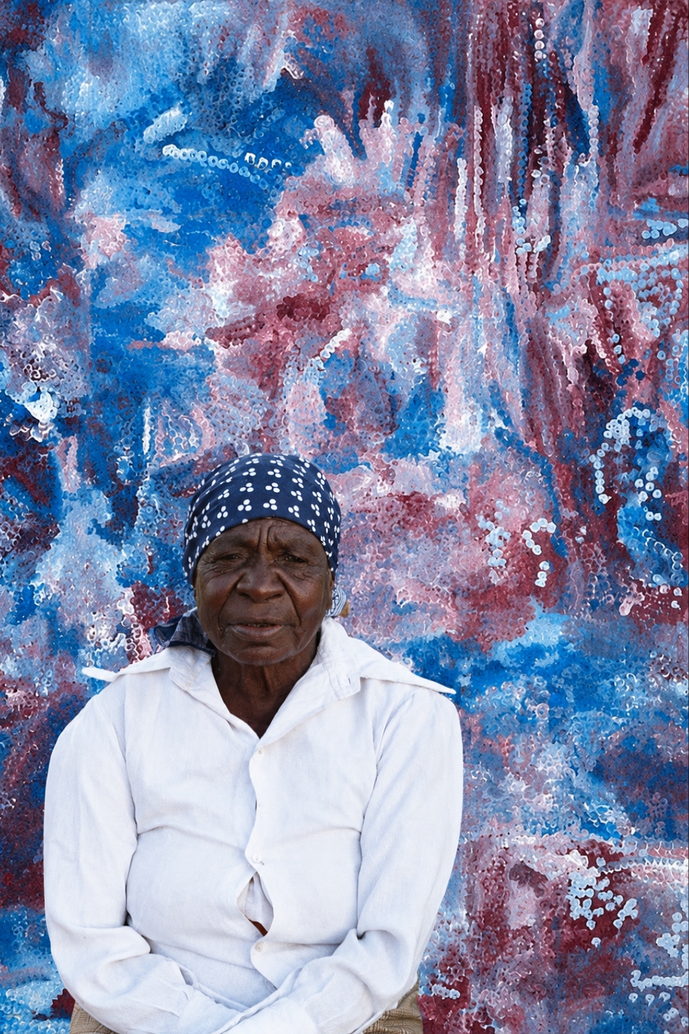 Emily Kame Kngwarreye – Aboriginal Artist Portrait of Emily Kame Kngwarreye, presented against a detail of her painting.