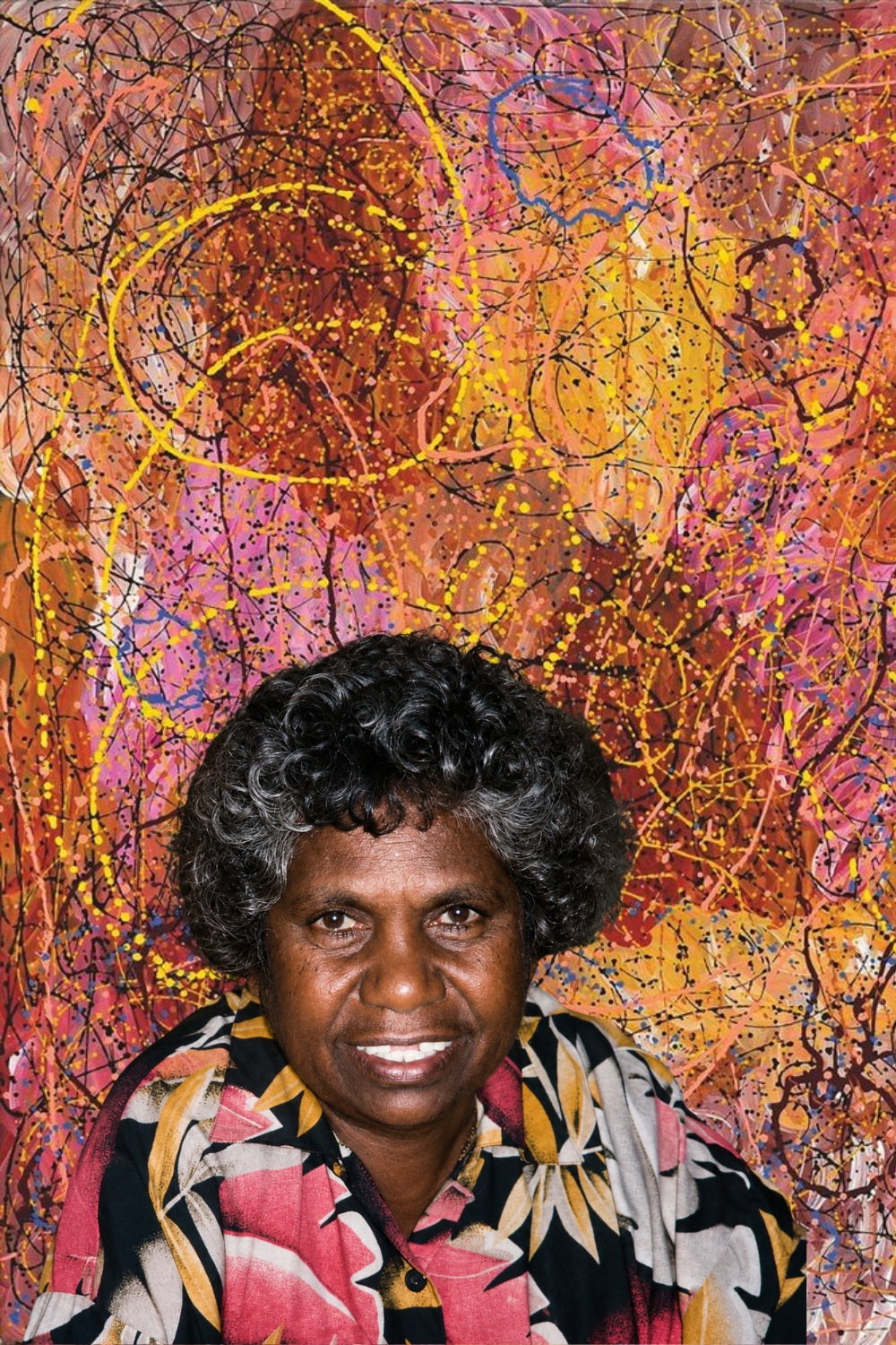 Portrait of Aboriginal artist Gloria Petyarre superimposed in front of one of her colourful paintings