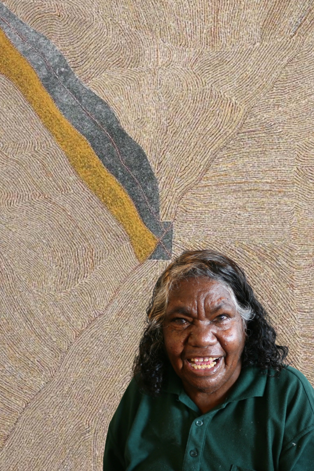 Kathleen Petyarre seated in front of one of her finely detailed paintings of Atnangkerre Country.