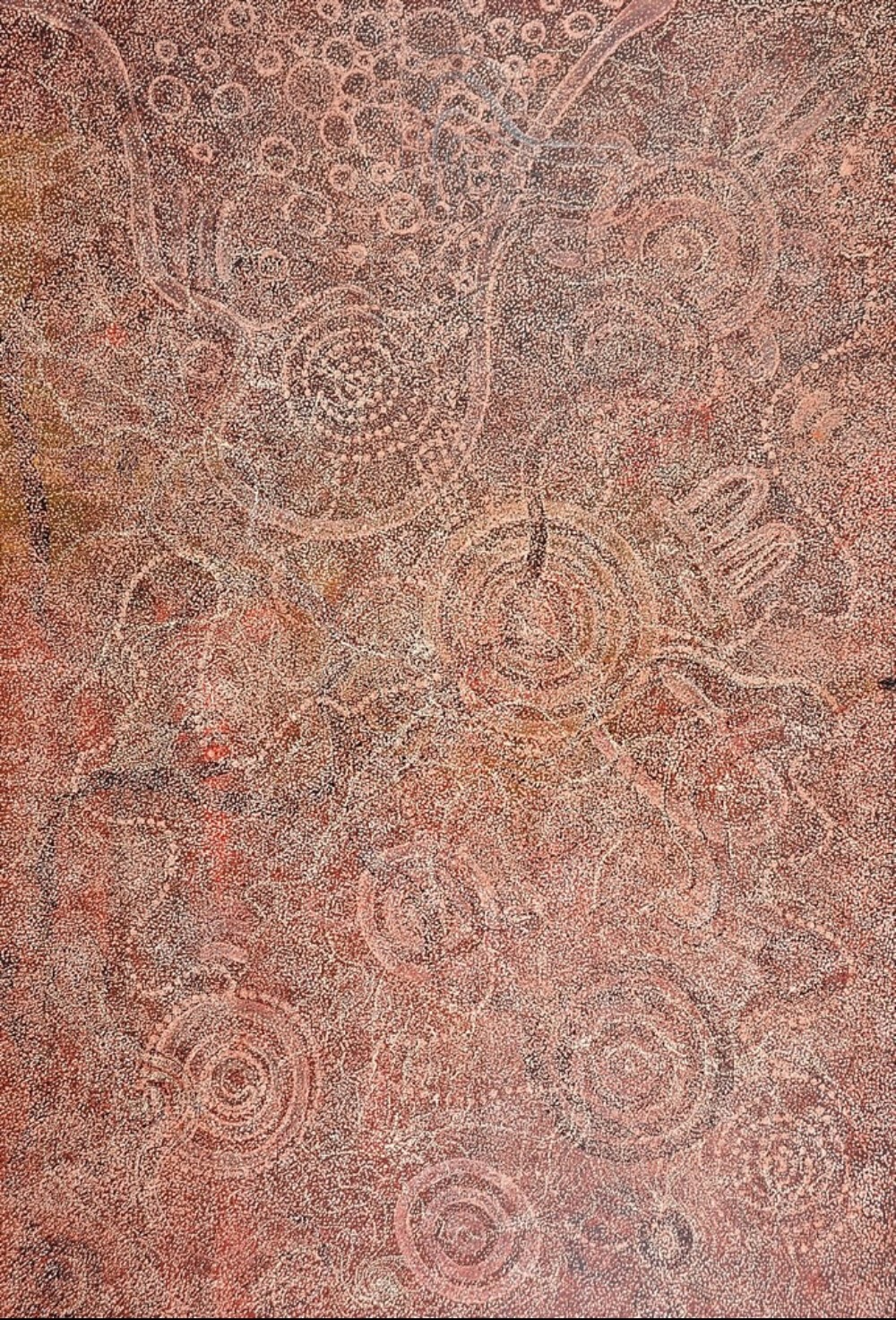 My Mother’s Country painting by Barbara Weir with fine dotting and traditional forms.  A densely dotted painting in earthy pink, red, brown and cream tones. Concentric circles, curved pathways and other forms appear faintly through the fine field of dots, almost like shadows beneath the surface.