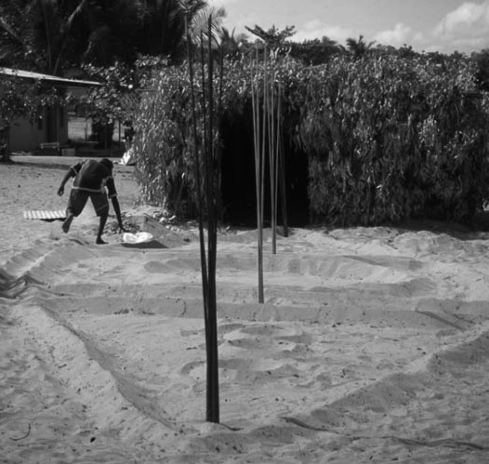 Yolŋu ceremonial yiŋapuŋapu sand sculpture in Arnhem Land, showing raised sand formations and upright poles associated with Aboriginal mortuary traditions.