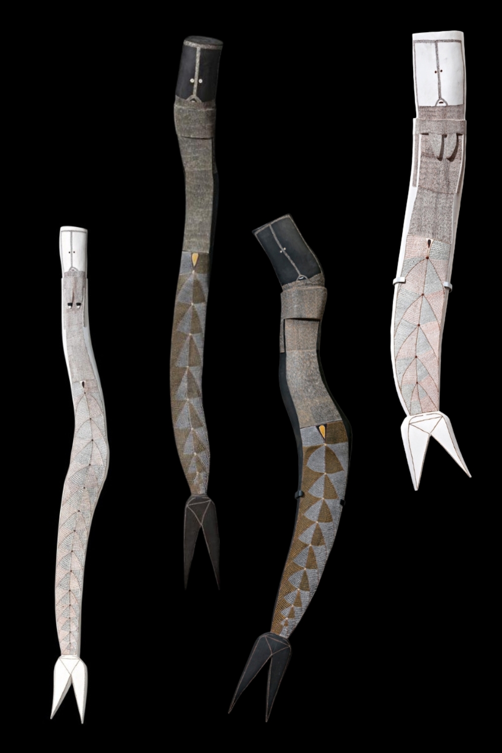 Four carved wooden Yawkyawk sculptures by Owen Yalandja, featuring elongated bodies, curved fish tails and intricate V-shaped scale patterns in natural earth pigments.