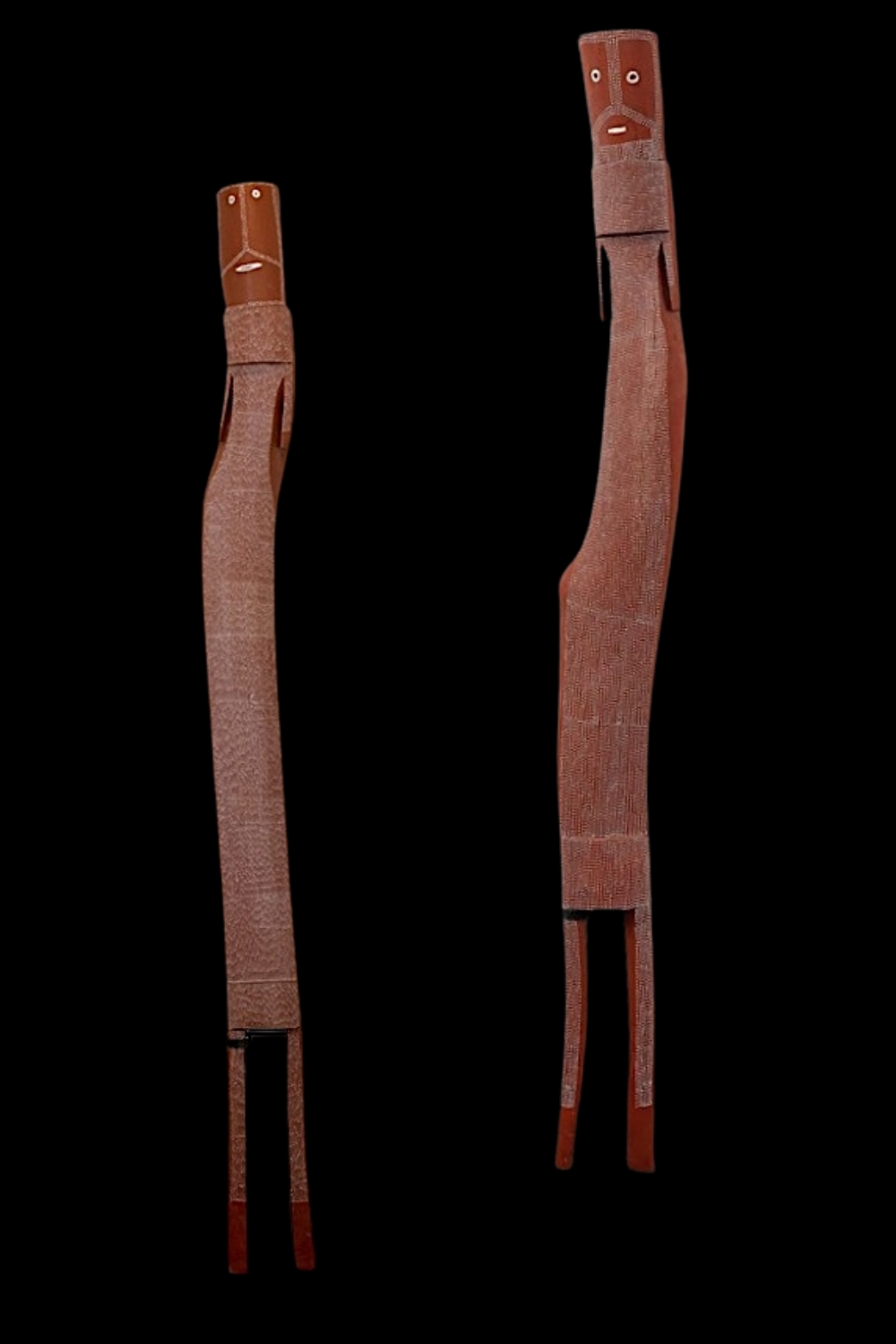 Two tall, slender wooden Mimih spirit sculptures by Owen Yalandja, with elongated bodies, carved arms and legs, stylised faces and fine ochre decoration.